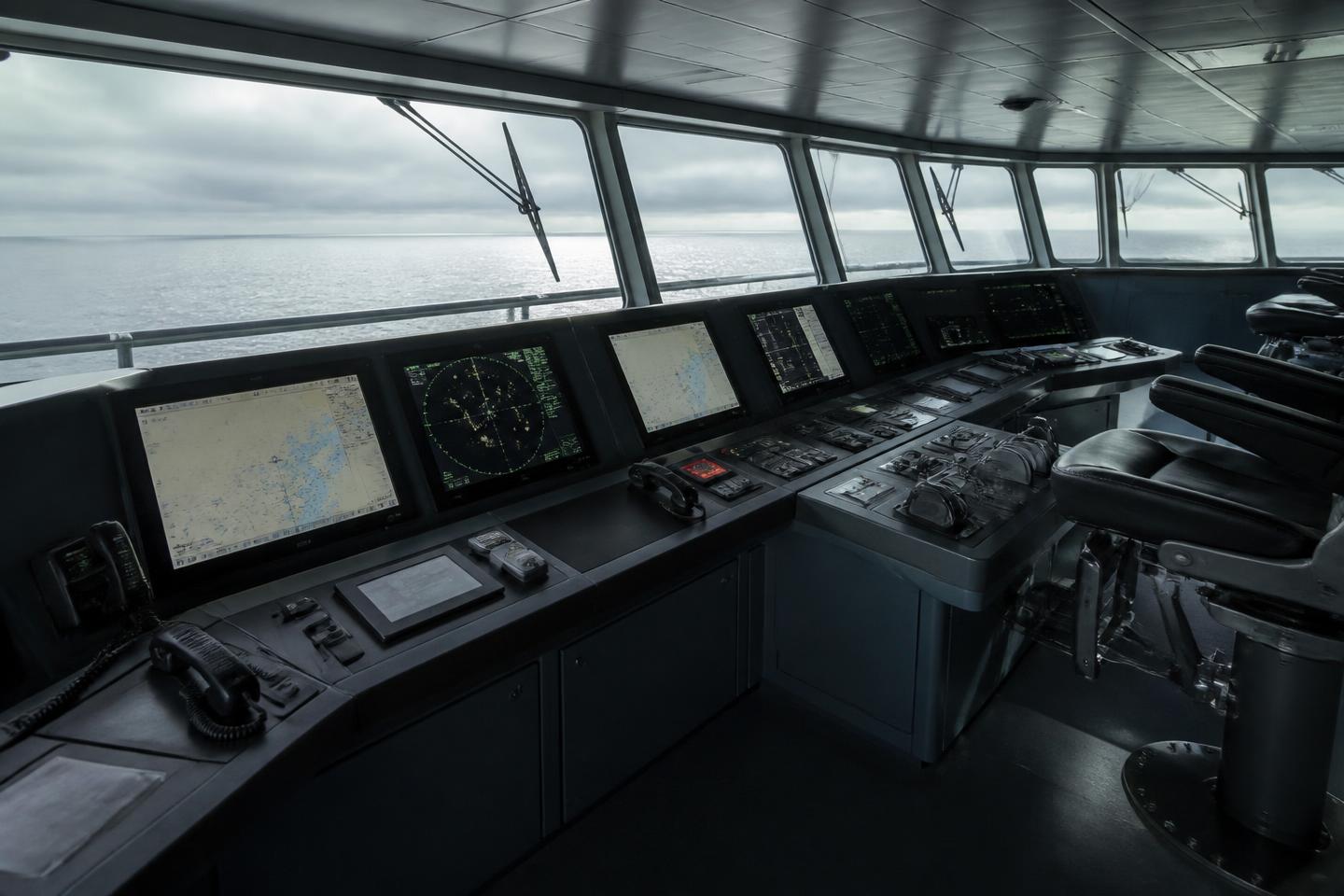 Navigation console and ECDIS displays on the bridge of a commercial vessel