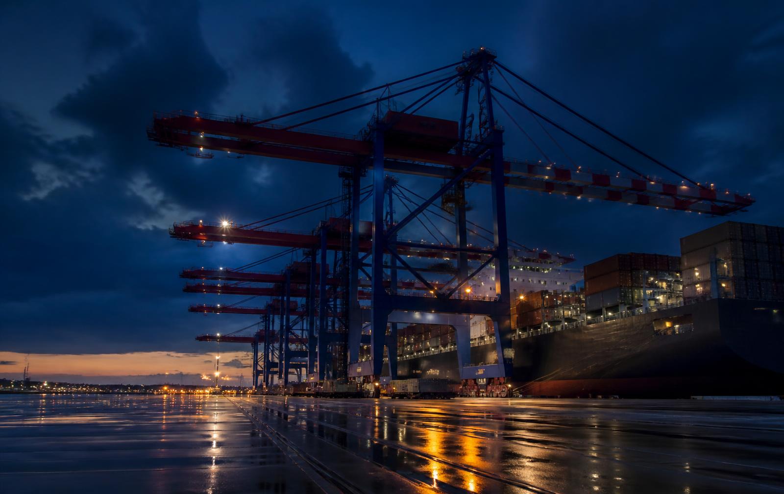Container terminal at dusk with gantry cranes working a vessel